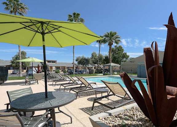A pool area with a table and chairs and umbrellas.