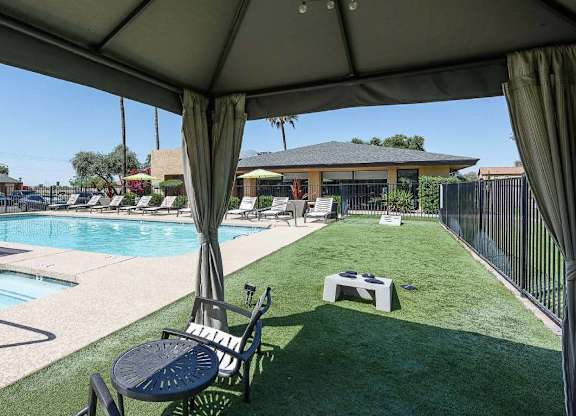 A pool area with a table and chairs under a canopy.