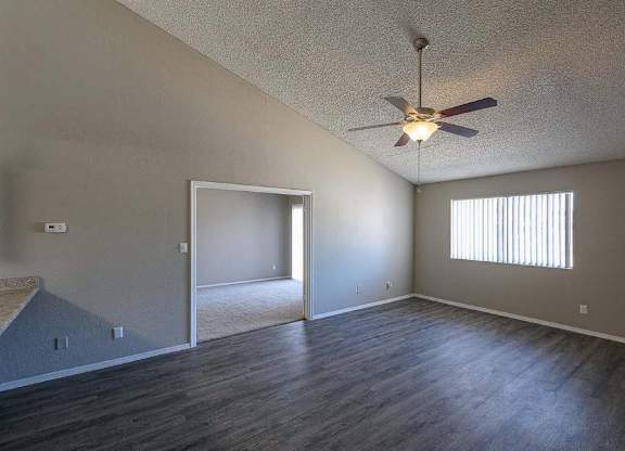 A room with a ceiling fan and a window with blinds.
