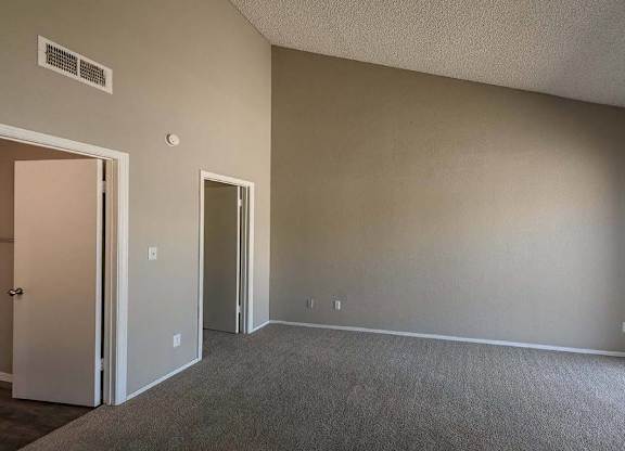 A room with a carpeted floor and two doors.