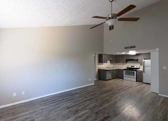 A room with a ceiling fan and a kitchenette.