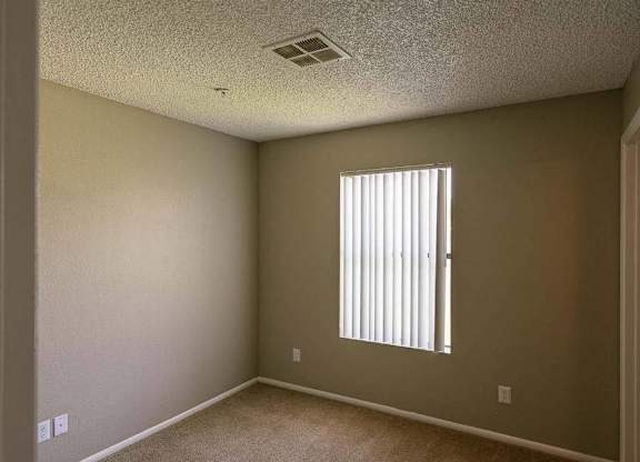A room with a window covered by white blinds.