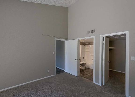 A room with a carpeted floor and two open doors leading to other rooms.