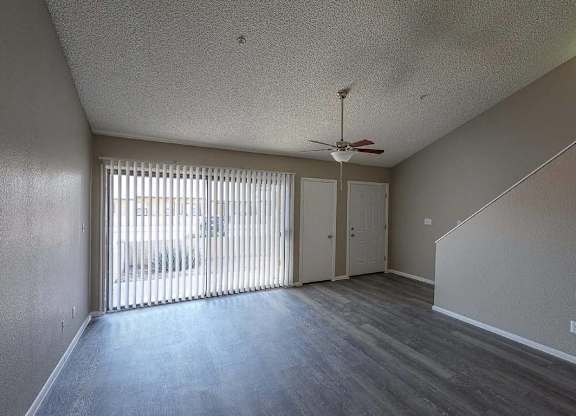 A room with a ceiling fan and sliding glass doors.