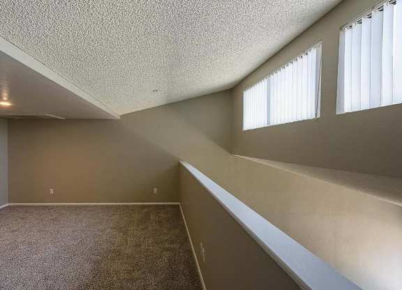 A room with a carpeted floor and a window with blinds.