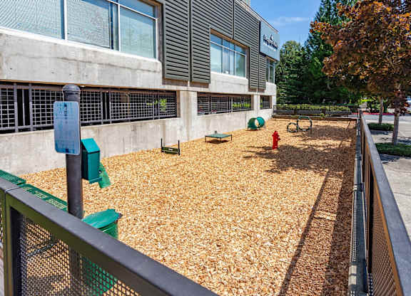 A playground with a green fence and a red fire hydrant.
