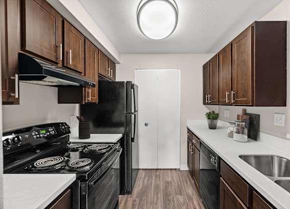 A kitchen with black appliances and brown cabinets.