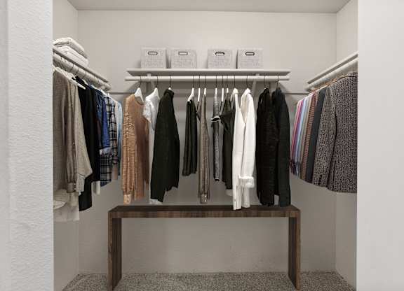 A row of clothes hanging on a rack in a white room.