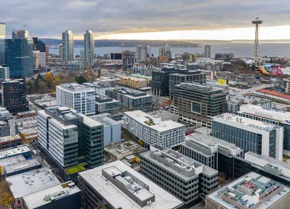 A cityscape with a variety of buildings and a tower in the background.