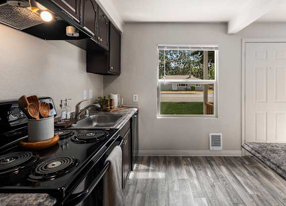A kitchen with a black stove top oven and wooden handles.