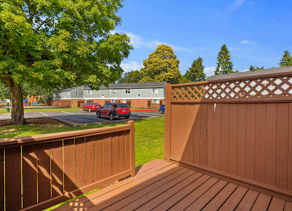 A wooden deck with a lattice fence and a tree in the background.