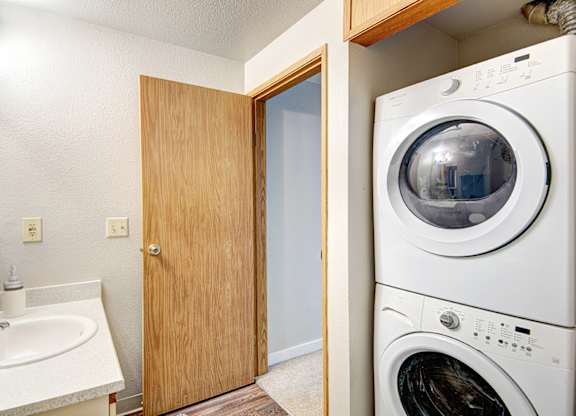 A white washing machine sits in a laundry room next to a sink.