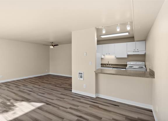 an empty living room and kitchen with a wood floor