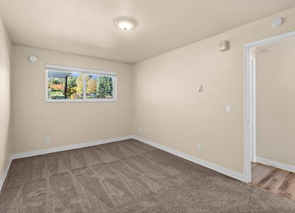an empty living room with carpet and a window