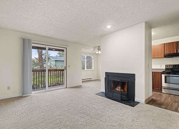 A living room with a fireplace and sliding glass doors. at Brookstone, SeaTac, WA