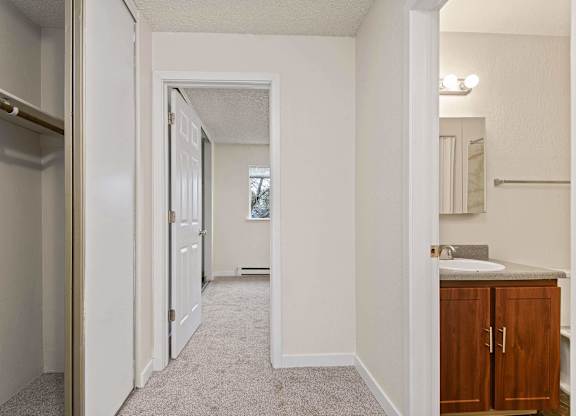 A hallway with a sink and a mirror on the wall. at Brookstone, SeaTac, 98198