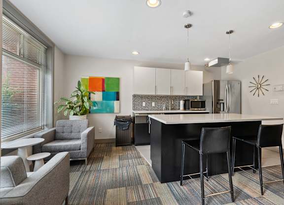 A modern kitchen with black bar stools and a white countertop.