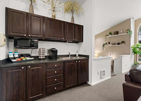 A kitchen with dark wood cabinets and a black microwave.