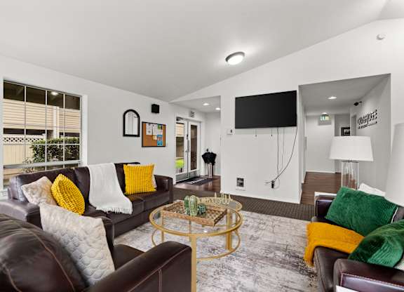A living room with a brown leather couch and a glass coffee table.