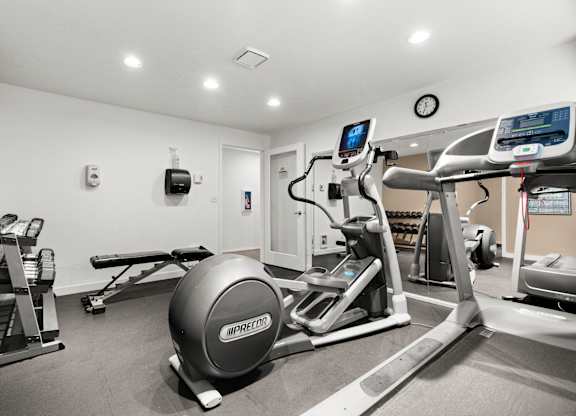 A gym with a treadmill, weights, and a ball.