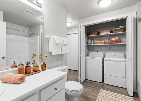 A white bathroom with a toilet, sink, and laundry room.