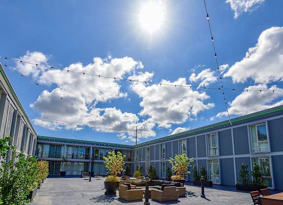 A sunny day at a modern outdoor seating area with a clear blue sky and fluffy white clouds.