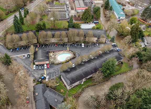 An aerial view of a parking lot with a building and trees.