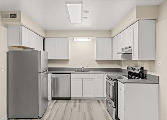 A modern kitchen with white cabinets and stainless steel appliances.