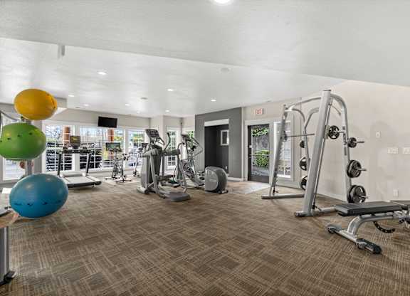 A gym with a variety of equipment including a treadmill, weights, and a bench.