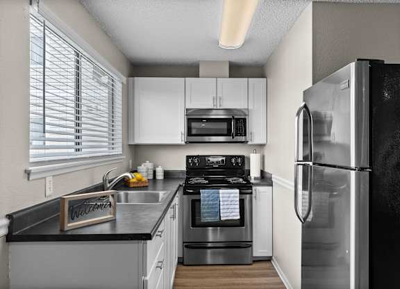 A kitchen with a black fridge and white cabinets.