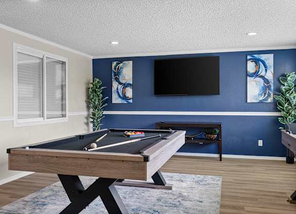 A pool table in a room with blue walls and a flat screen TV.