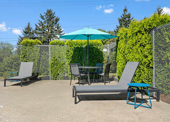 A patio with a table, chairs, and an umbrella.