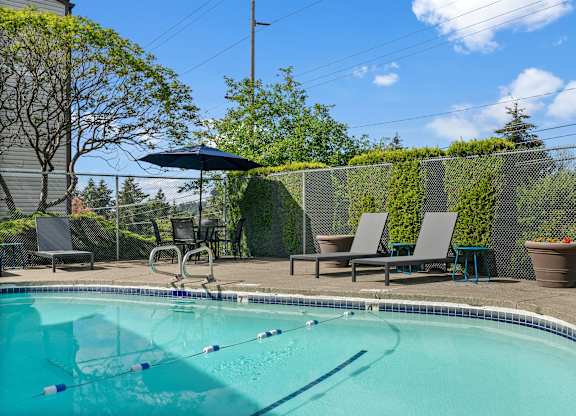 A swimming pool with a diving board and lounge chairs.