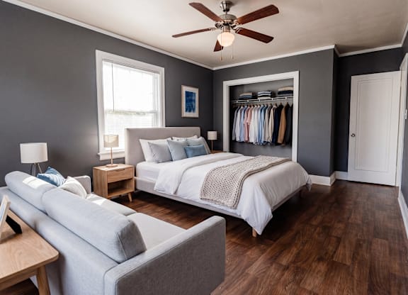 A bedroom with a bed, a couch, and a ceiling fan.