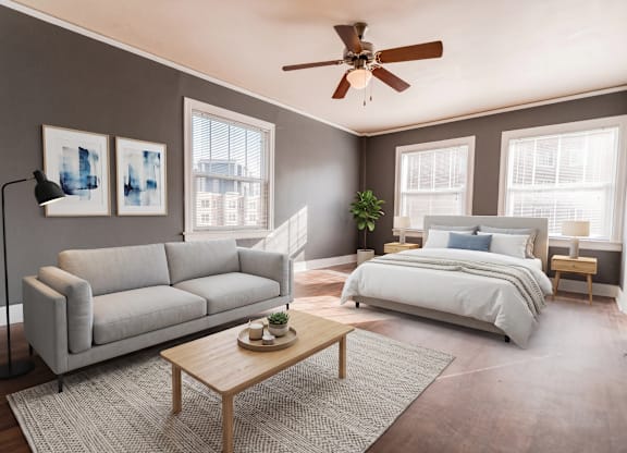 A bedroom with a large bed, a couch, a coffee table, and a ceiling fan.
