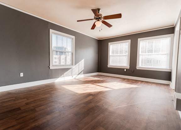 A room with a ceiling fan and wooden flooring.