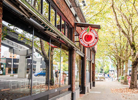 A red sign with a white apple on it is on the side of a building.