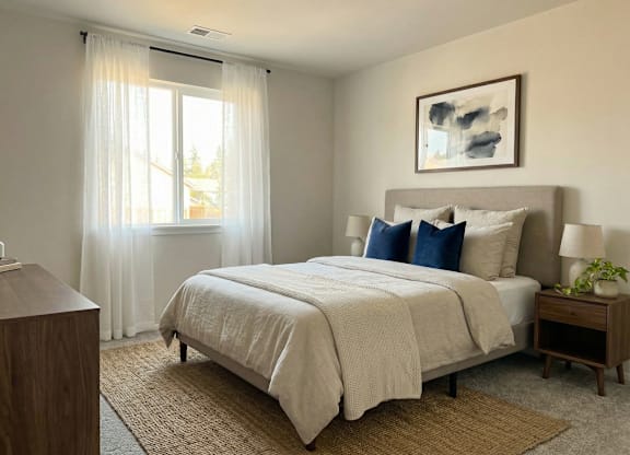 A bedroom with a large bed and a painting on the wall.