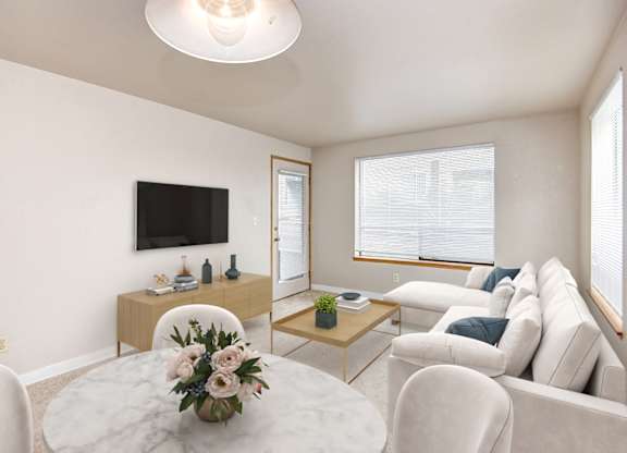A living room with a white couch, a coffee table, and a flat-screen TV.