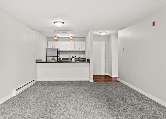 A spacious kitchen with white cabinets and a grey carpet.