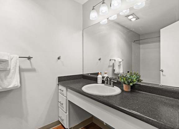 A bathroom with a sink, mirror, and a towel rack.