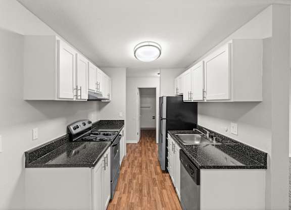 A modern kitchen with black countertops and white cabinets.