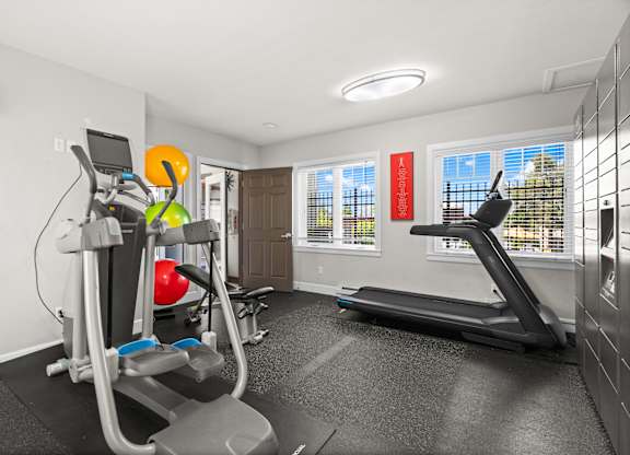 A home gym with a treadmill, elliptical trainer, and other exercise equipment.