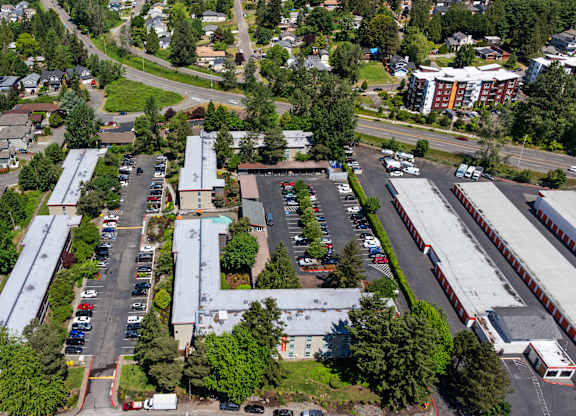 A parking lot is surrounded by buildings and trees.