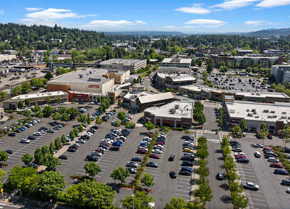 A parking lot with cars and a large building with a sign that says "Amazon" in the background.
