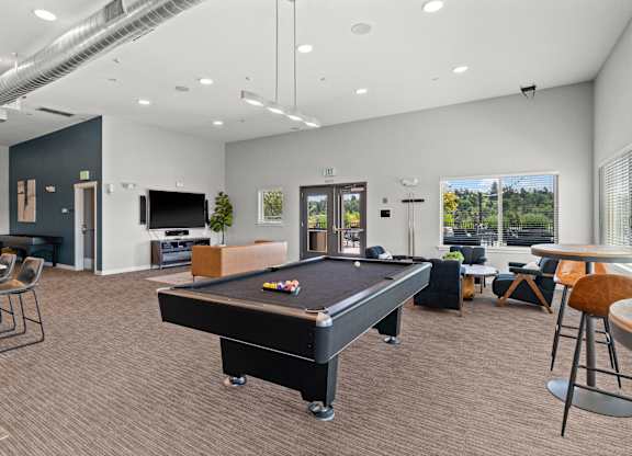 A room with a pool table and a bar area.