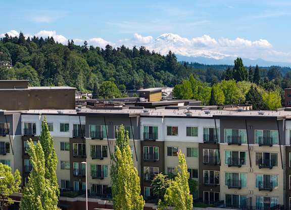 Apartment buildings with trees in front and mountains in the background.