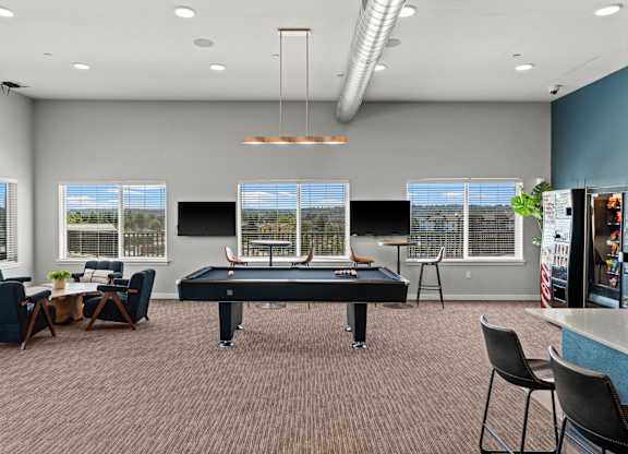 A room with a pool table and chairs.
