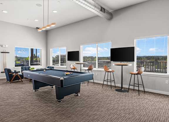 A room with a pool table and bar stools.