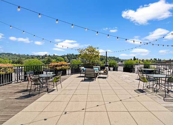 A patio with tables and chairs under a string of lights.